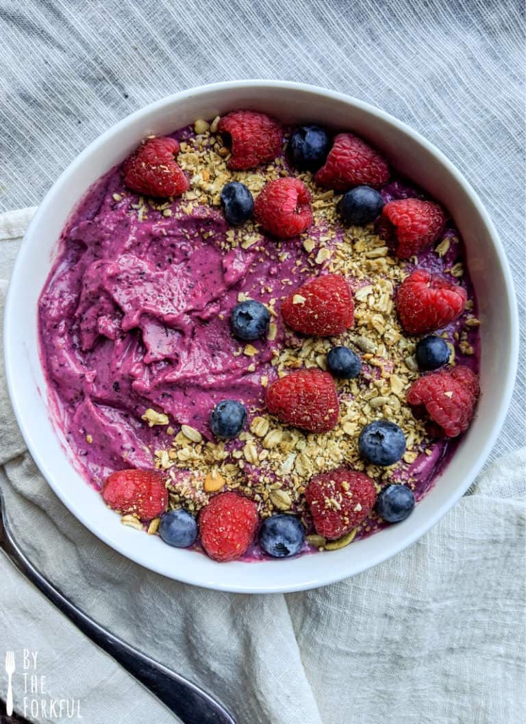 Frozen fruit smoothie bowl topped with raspberries, blueberries, and granola.