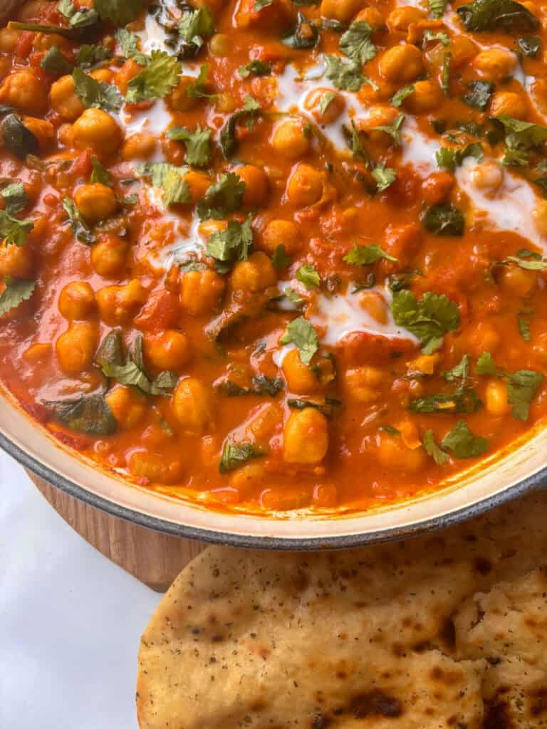 a pan of chickpea and spinahc curry with a side of garlic naan