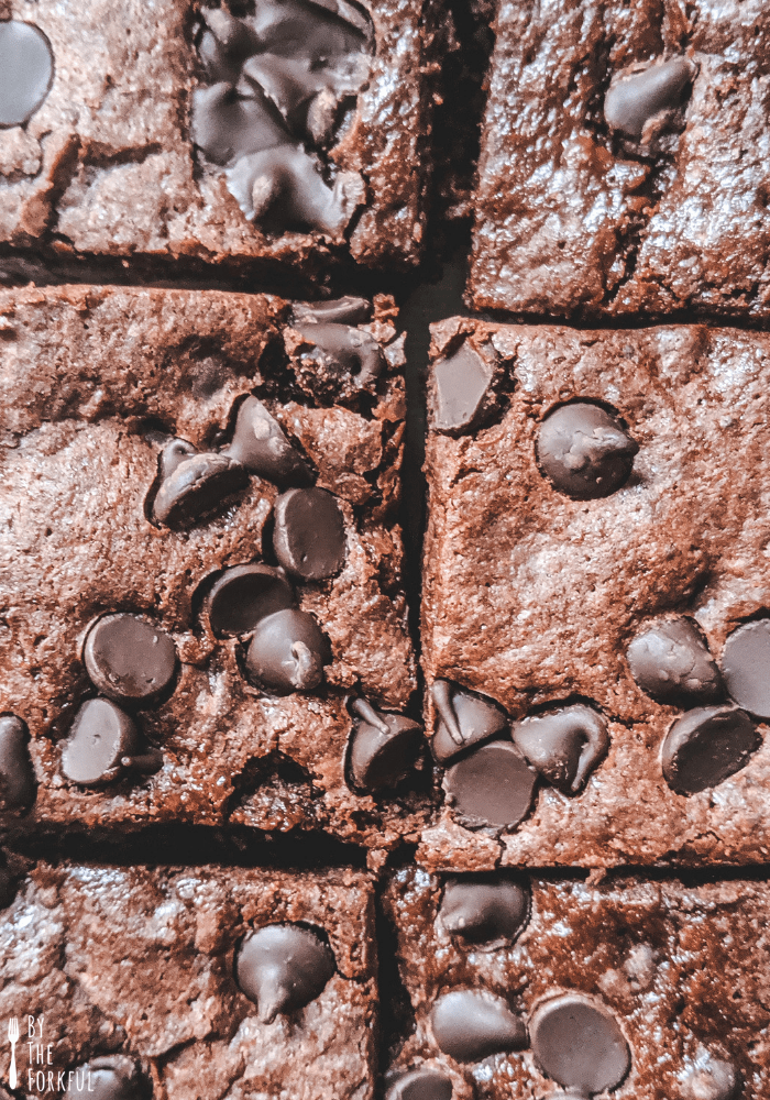 A close-up shot of vegan chocolate brownies cut into squares, topped with vegan chocolate chips.