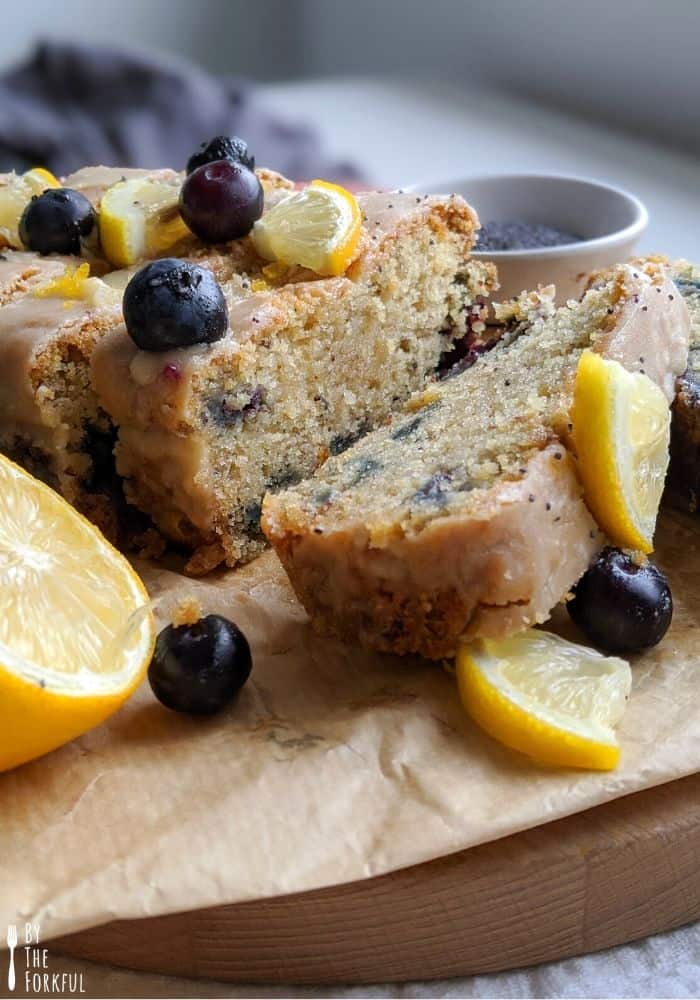 A side view of this lemon blueberry poppyseed cake which is topped with a fresh lemon icing and fresh blueberies and lemon slices.