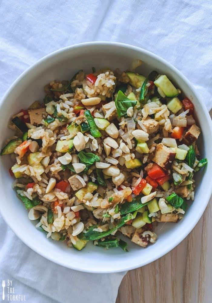 Green curry fried rice in a bowl topped with roasted peanuts.