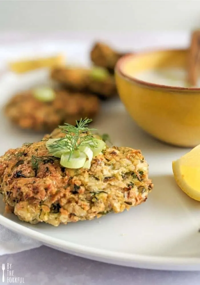 Vegan courgette fritters topped with spring onion and fresh dill and served with a cool vegan lemony-yoghurt dip.