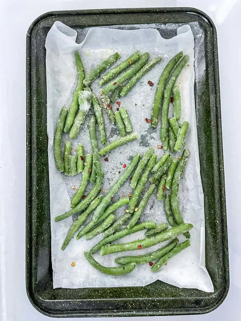 The frozen green beans now coated in olive oil and with the herbs and spices added.