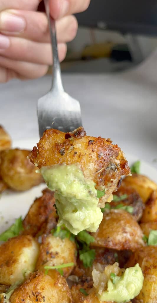 Crispy mexican potato dipped in avocado sauce and speared by a fork