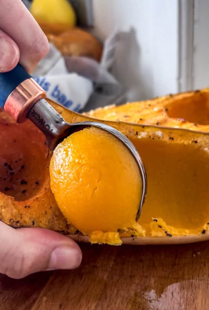 roasted butternut squash being scooped out of the flesh
