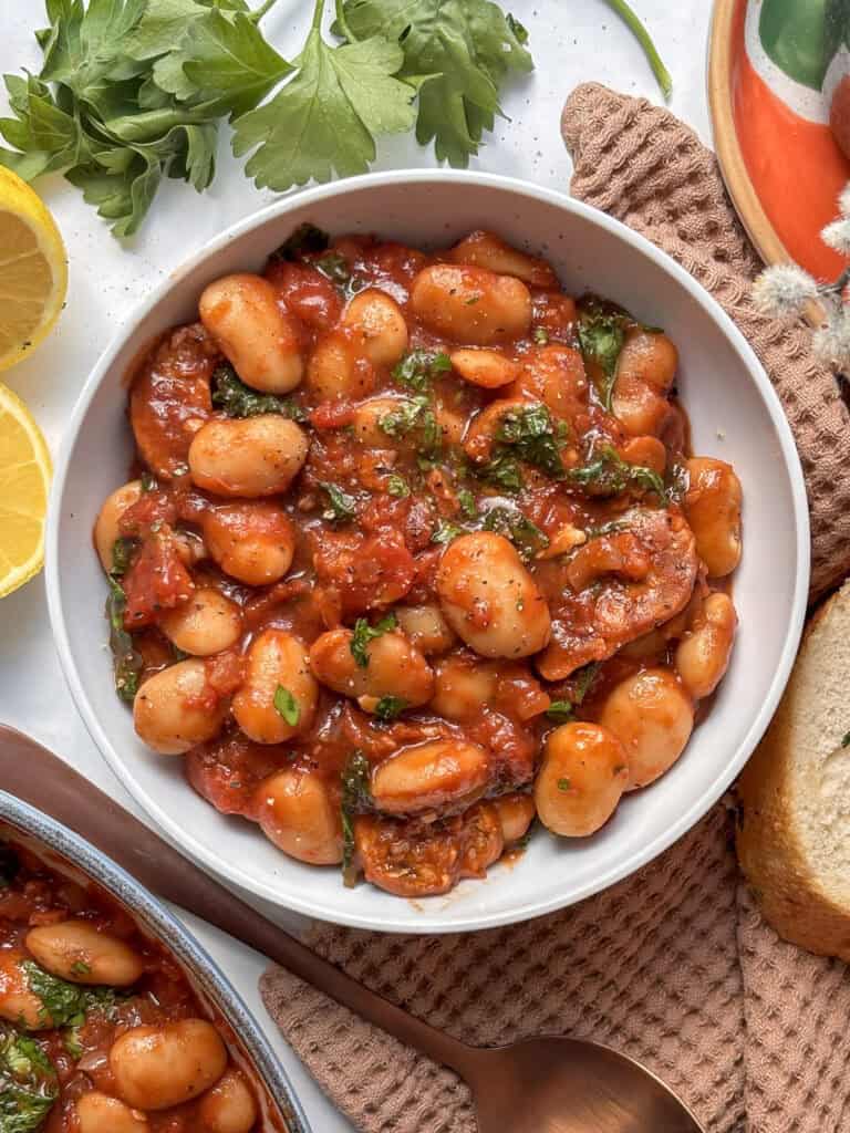butter bean and chorizo stew in a white bowl with chopped parsley