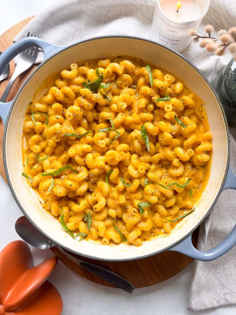 a casserole dish of creamy butternut squash pasta topped with black pepper and sage