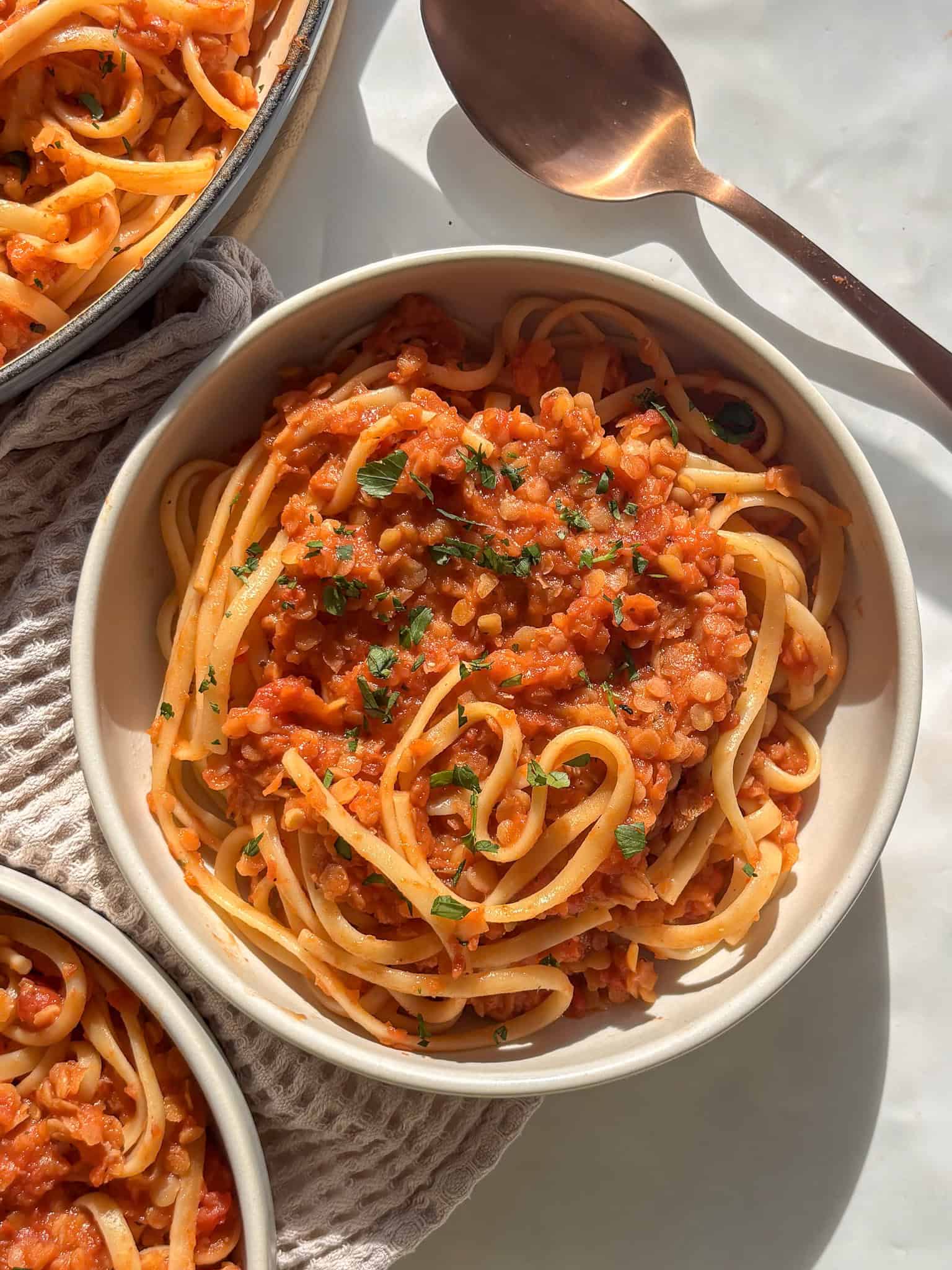 a bowl of lentil bolognese over linguine, topped with fresh parsley