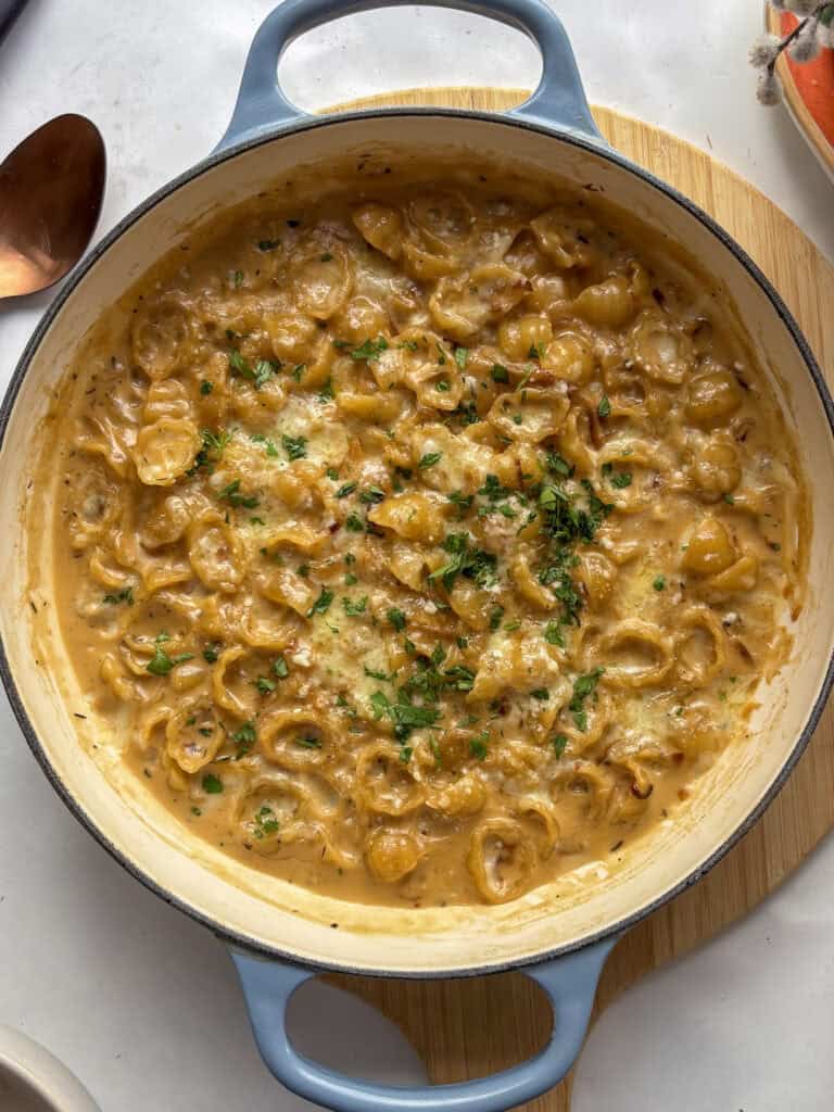 a casserole pan of cheesy French onion pasta topped with fresh herbs