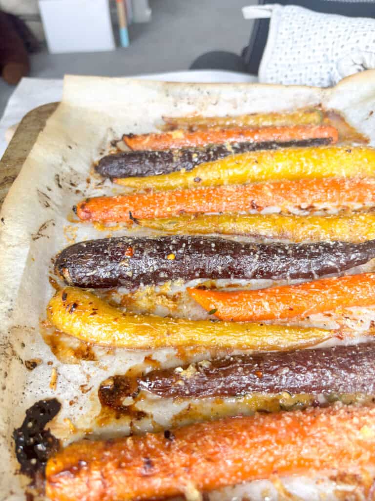 Beautifully roasted honey butter carrots on the baking tray, topped with the honey butter sauce and cheese/breadcrumb mixture