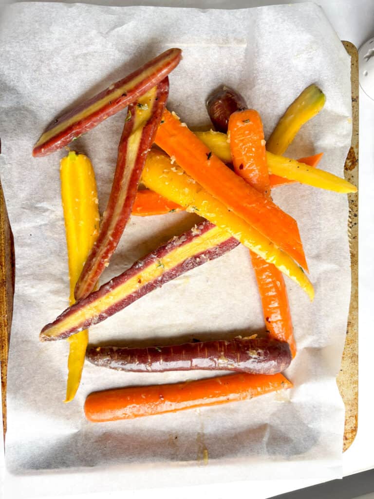 rainbow carrots in a honey butter sauce on a baking tray
