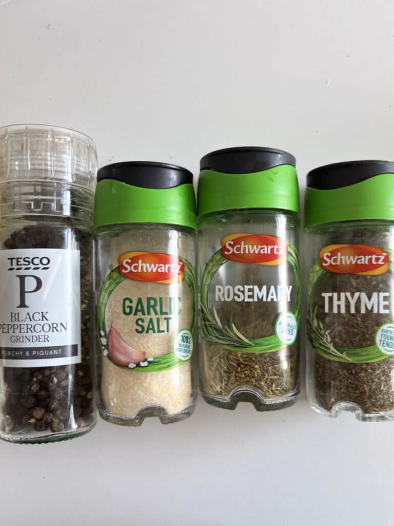 a photo of the four seasonings used for this roasted carrots and green beans recipe: black pepper, garlic salt, rosemary, and thyme.