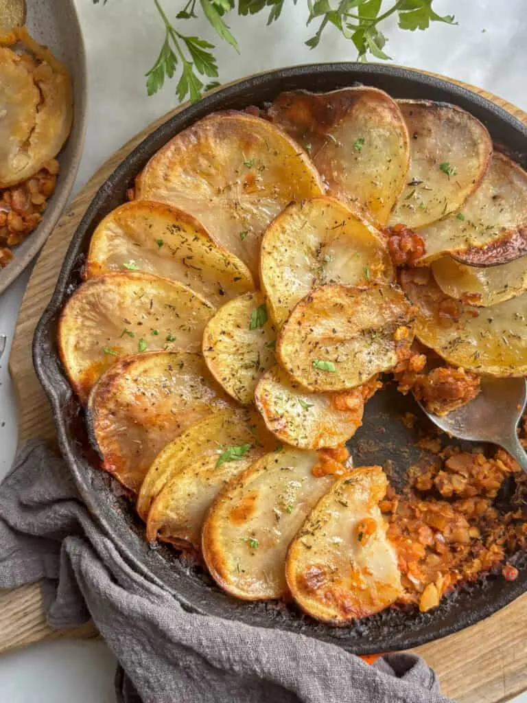 an overhead shot of the lentil and potato hotpot with a serving taken out of the dish