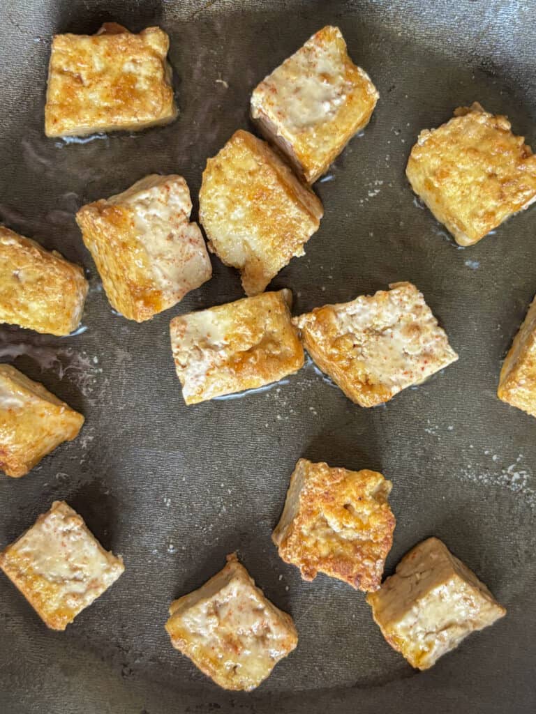 the tofu cooking in a saucepan, turning golden and crispy