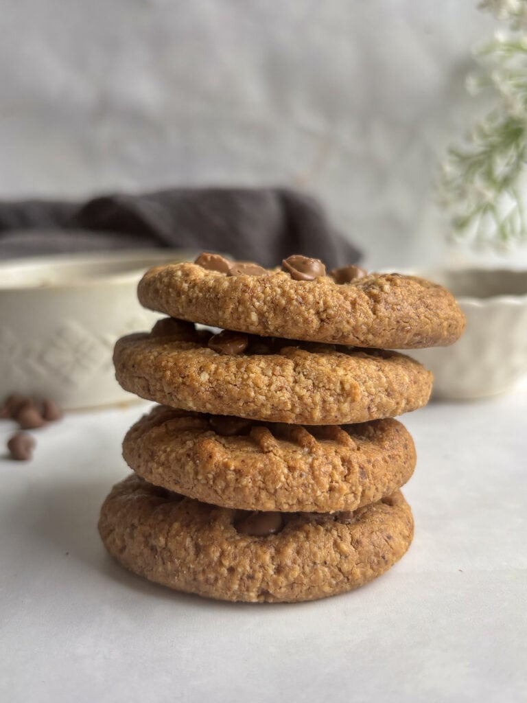 a stack of 3 ingredient almond butter cookies topped with chocolate chips.