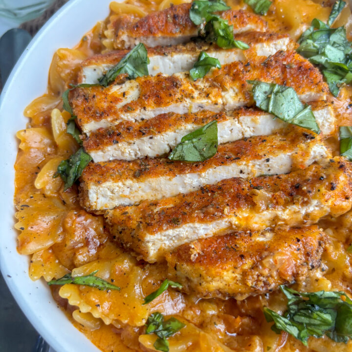 a close up shot of marry me chicken pasta with a spicy, crispy sliced tofu fillet on top