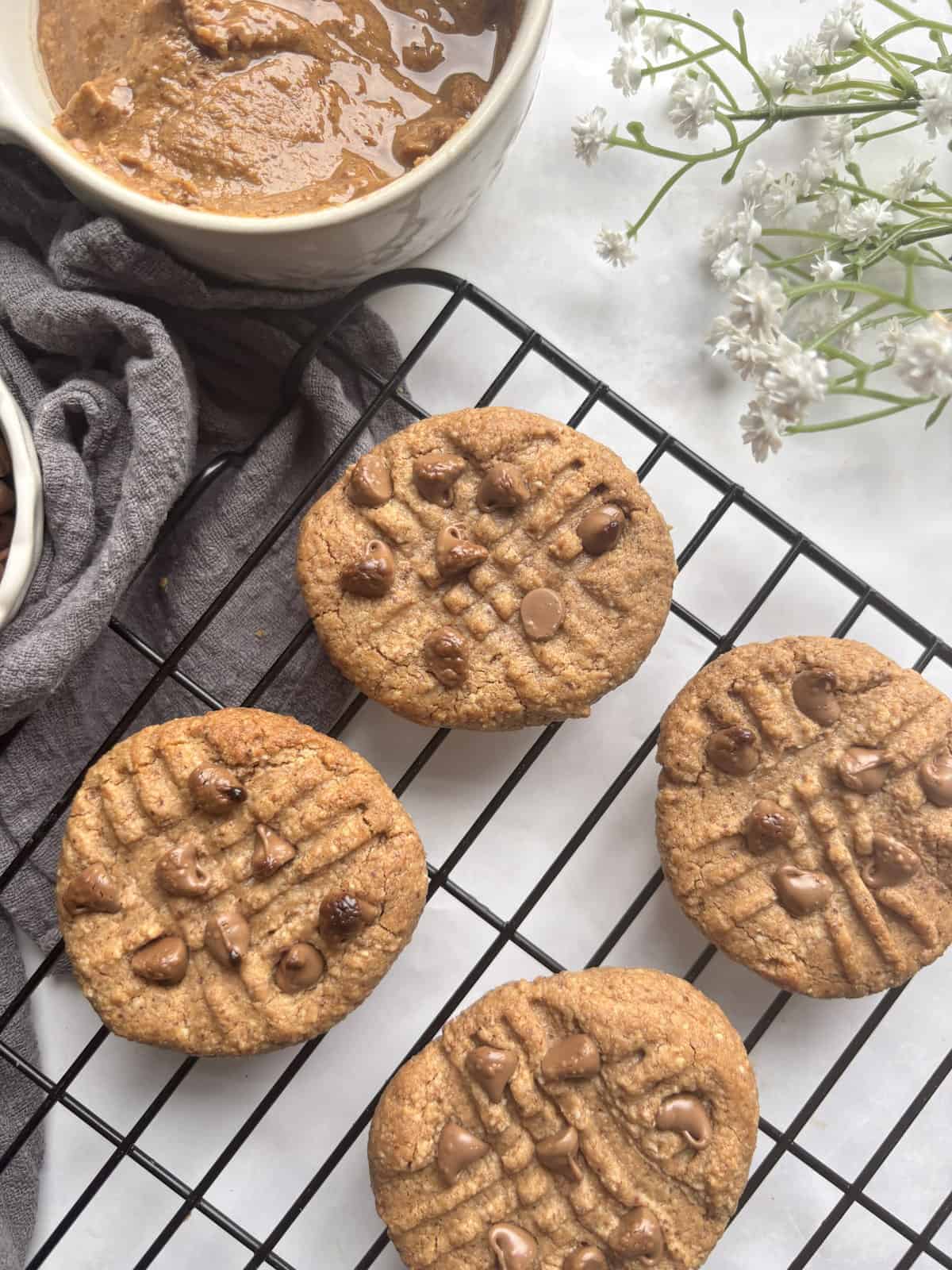 a cooling rack with almond butter cookies on it, studded with chocolate chips