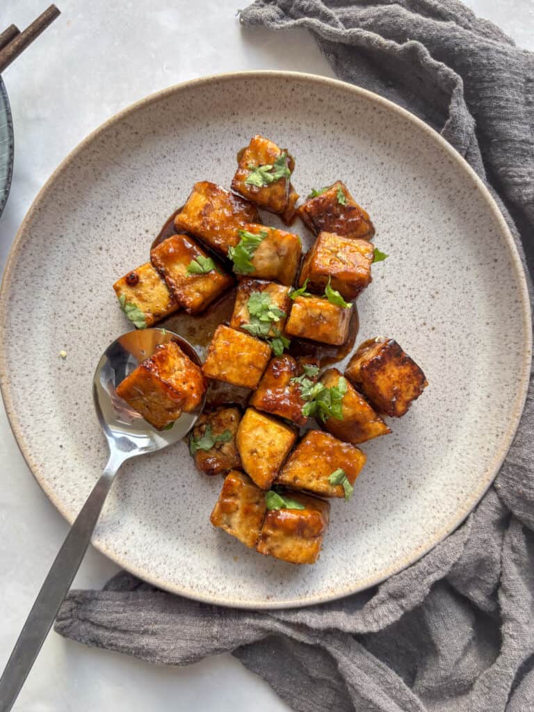 an overhead shot of a grey speckled plate with the crispy marinated tofu on, topped with chopped cilantro