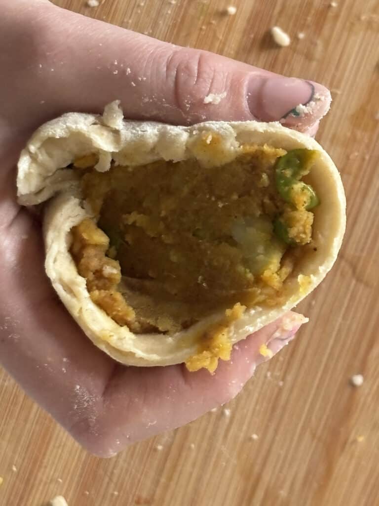 the samosa dough cone stuffed with the potato filling and ready to be sealed and baked