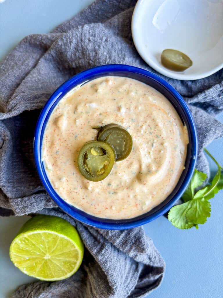 a creamy jalapeno sauce in a blue bowl with sliced jalapenos on top