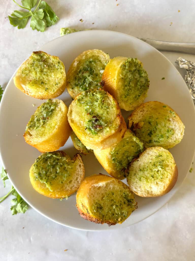 a white plate with garlic baguette slices on it.