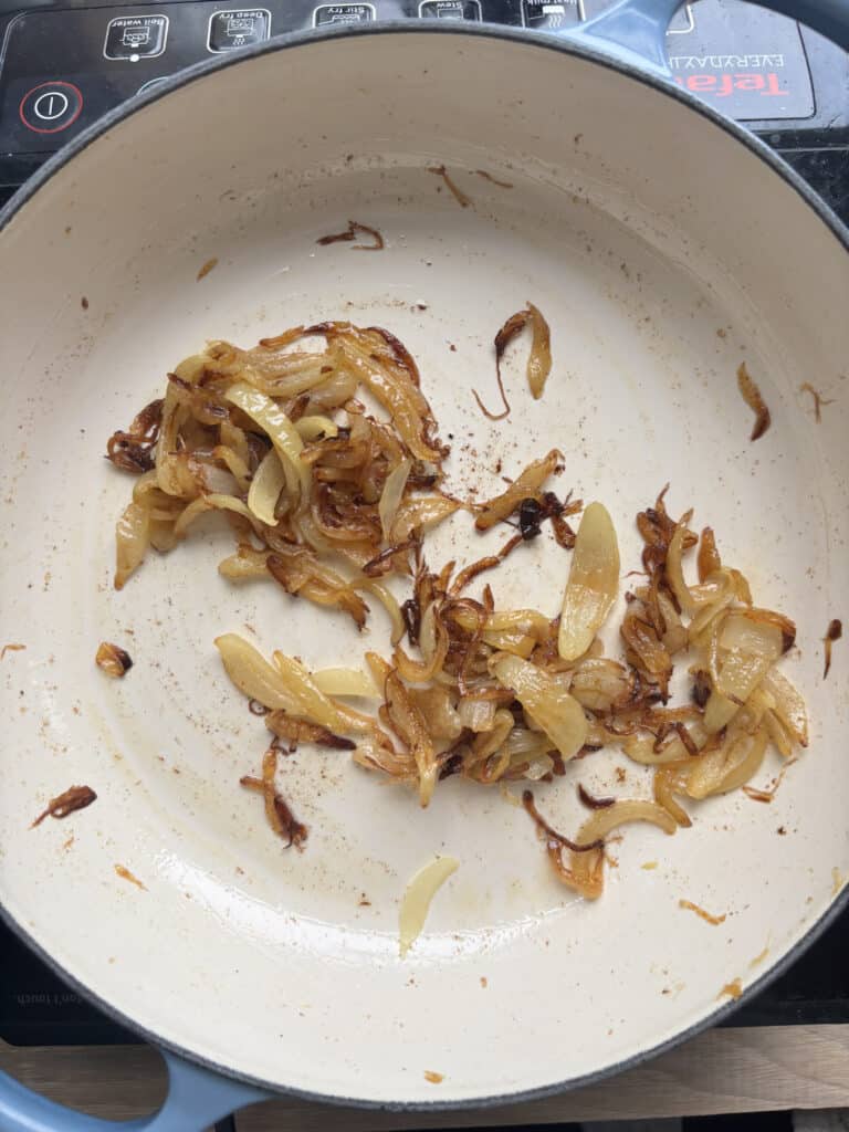 the caramelized onions, golden brown in color, in the white pan