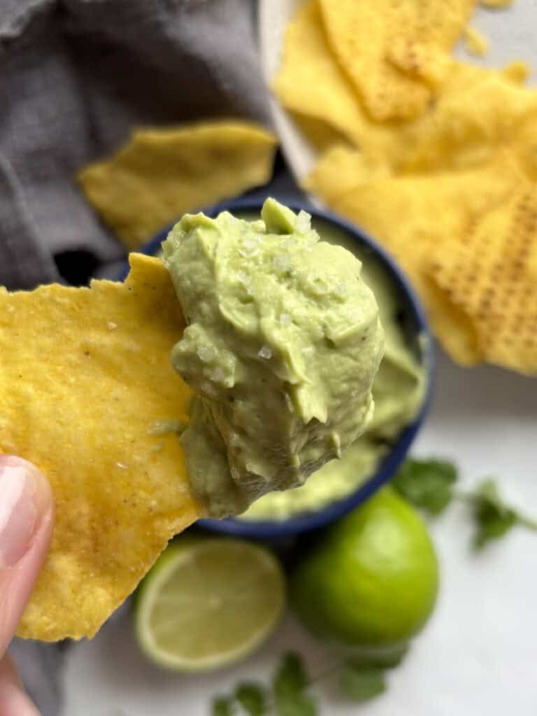 a close up shot of a tortilla chip loaded with the avocado lime crema sauce