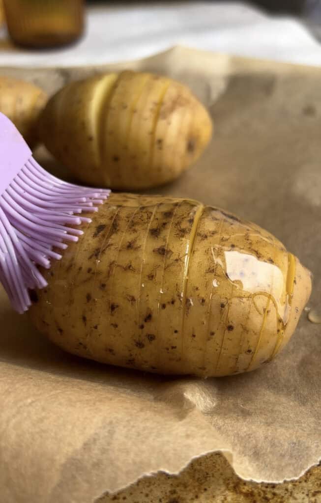 hasselback potato being brushed with oil