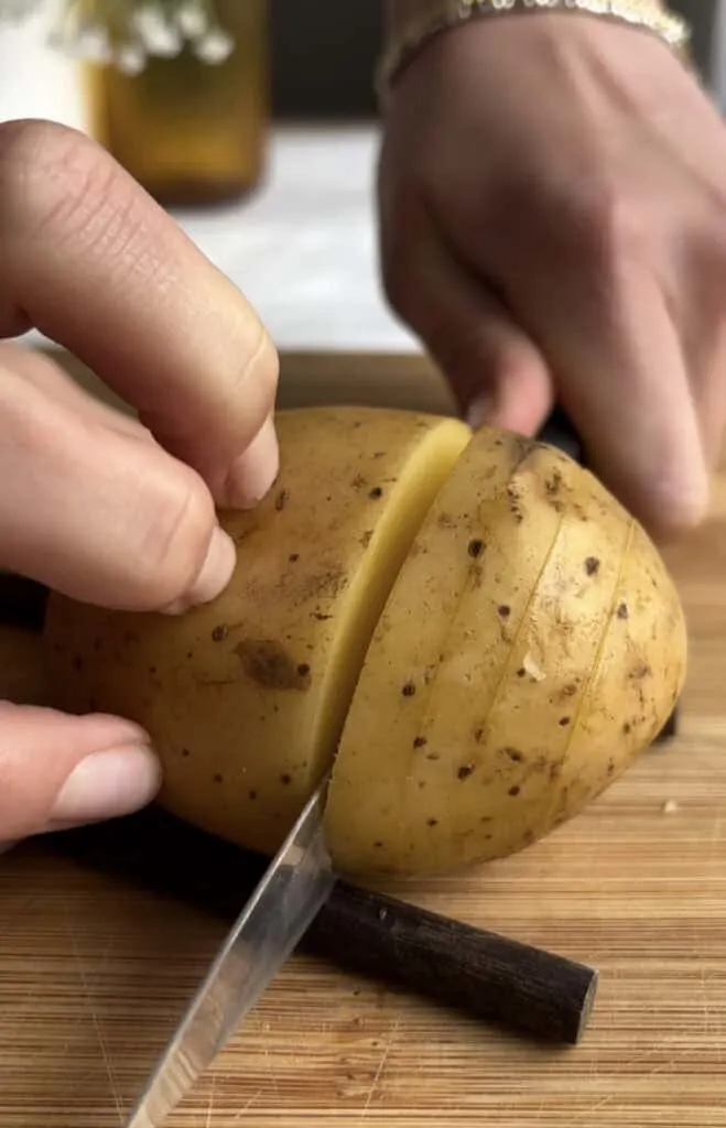 potato lined by chopsticks and having slits cut into it