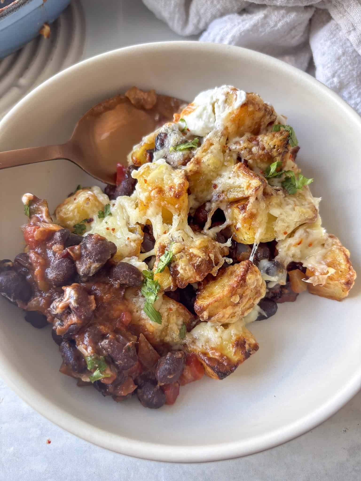 a bowl of smoky chipotle black beans, crispy cubed potatoes, cheese, and yogurt to top it off