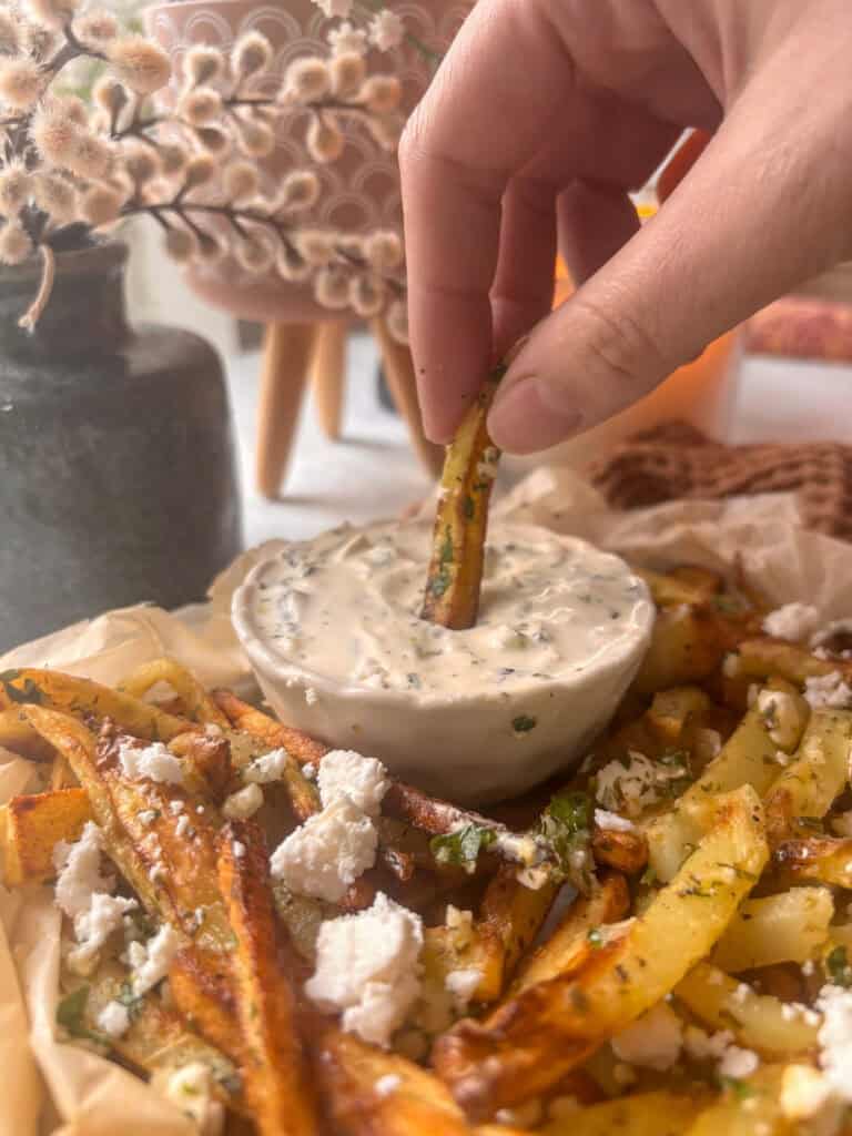 Greek fries - one fry is being dipping into the Tzatziki