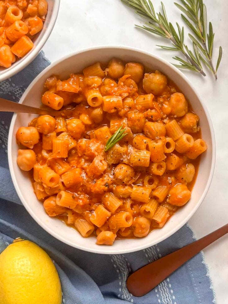 a bowl of pasta e ceci (pasta with chickpeas) topped with a little olive oil and a sprig of rosemary