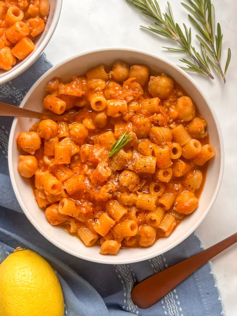 a bowl of pasta e ceci (pasta with chickpeas) topped with a little olive oil and a sprig of rosemary