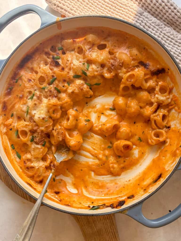 overhead shot of casserole dish of buffalo mac and cheese, with a spoon having portion some of it out