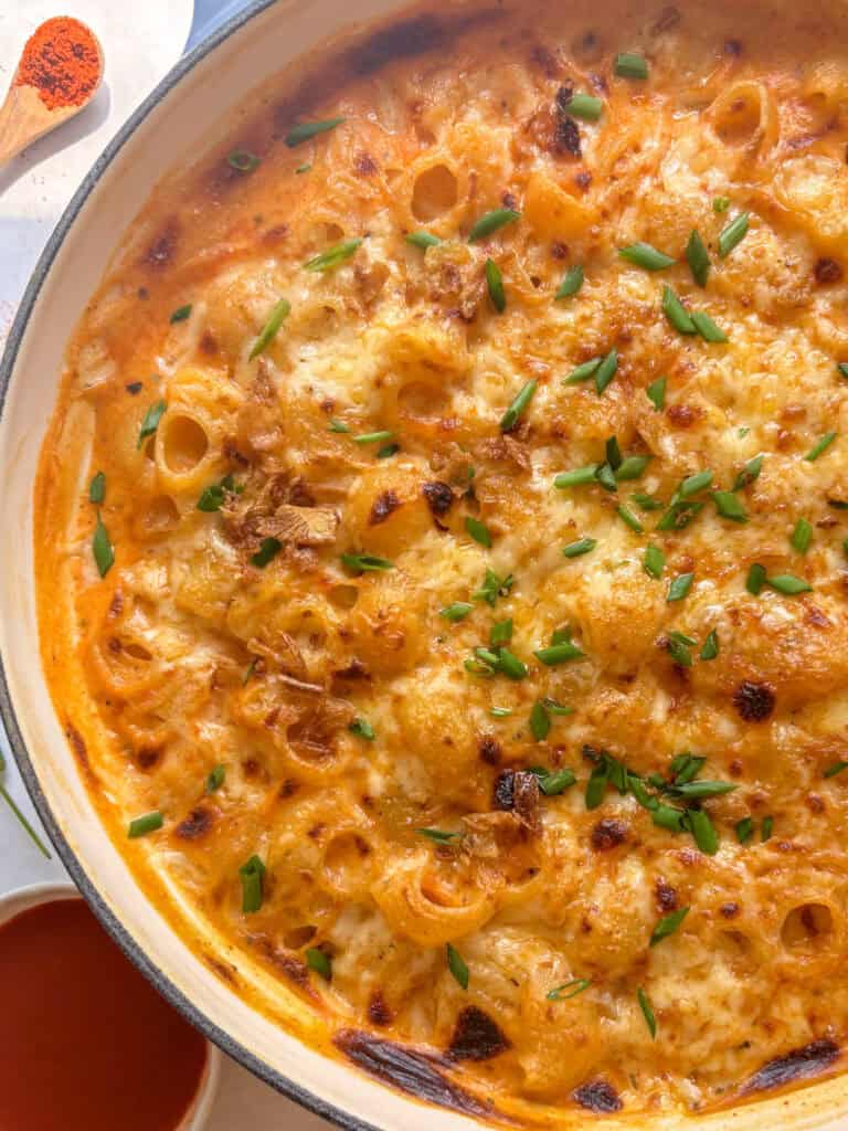 close up shot of the cheesy grilled top of the buffalo mac and cheese, topped with crispy onion and chives