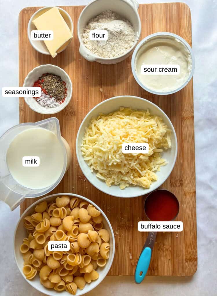 ingredients shot for buffalo mac and cheese: butter, flour, milk, buffalo sauce, pasta, cheese, sour cream, and seasonings