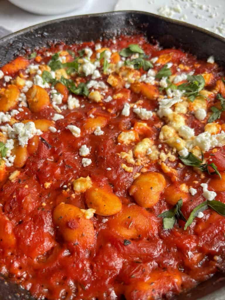 a close up shot of the greek giant baked beans topped with feta and parsley
