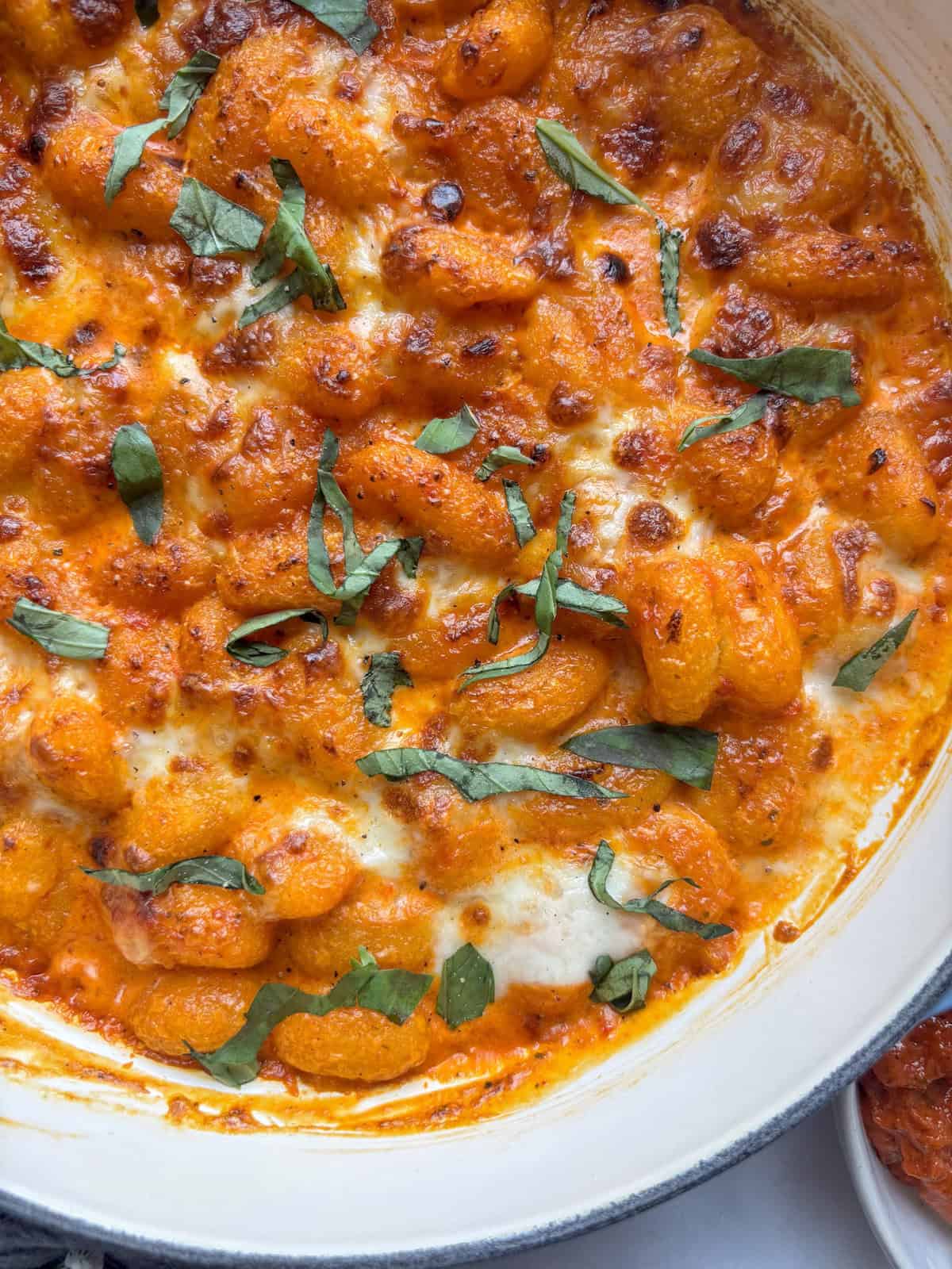 close up shot of creamy red pesto gnocchi in the pan