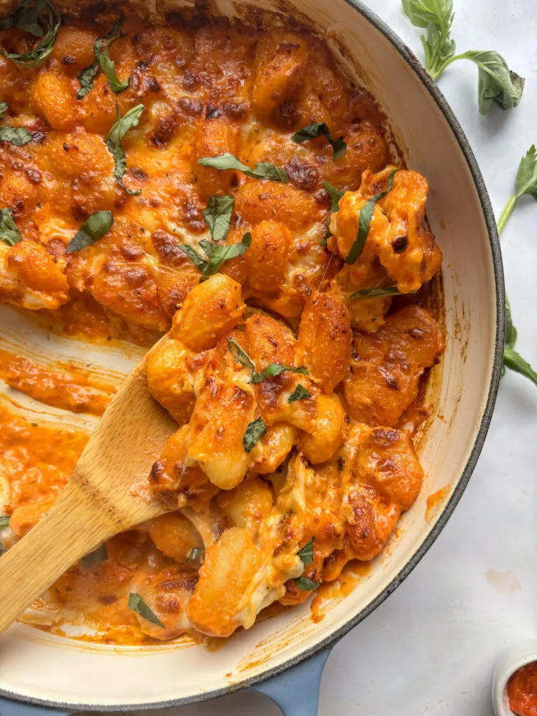 an overhead shot of the red pesto gnocchi being scooped out by a spoon