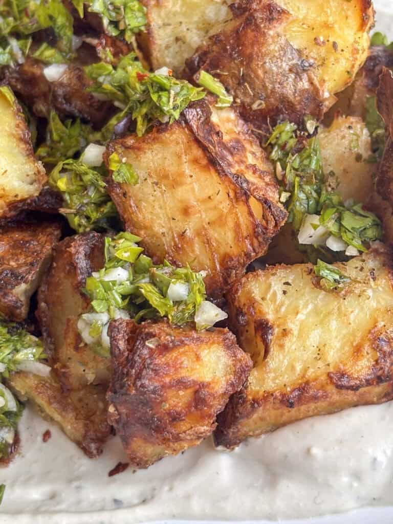 close up shot of a crispy za'atar potato topped with zingy parsely and garlic and za'atar seasoning