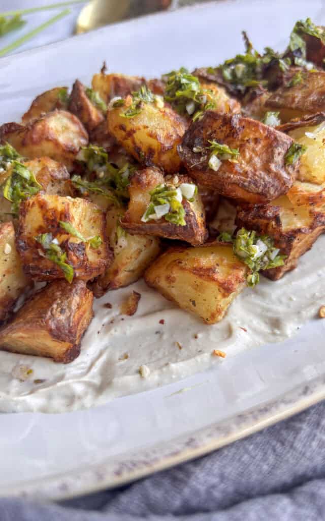 a close up shot of crispy roasted za'atar potatoes topped with zingy parsley