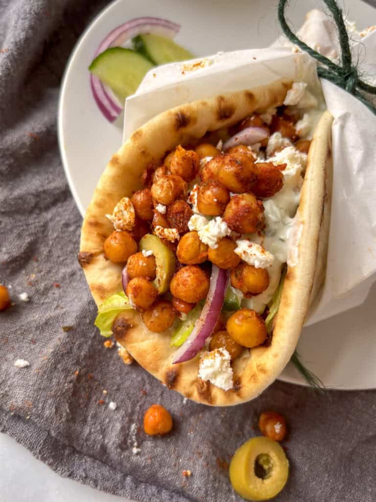 a roasted chickpea gyro wrapped in baking paper on a white plate