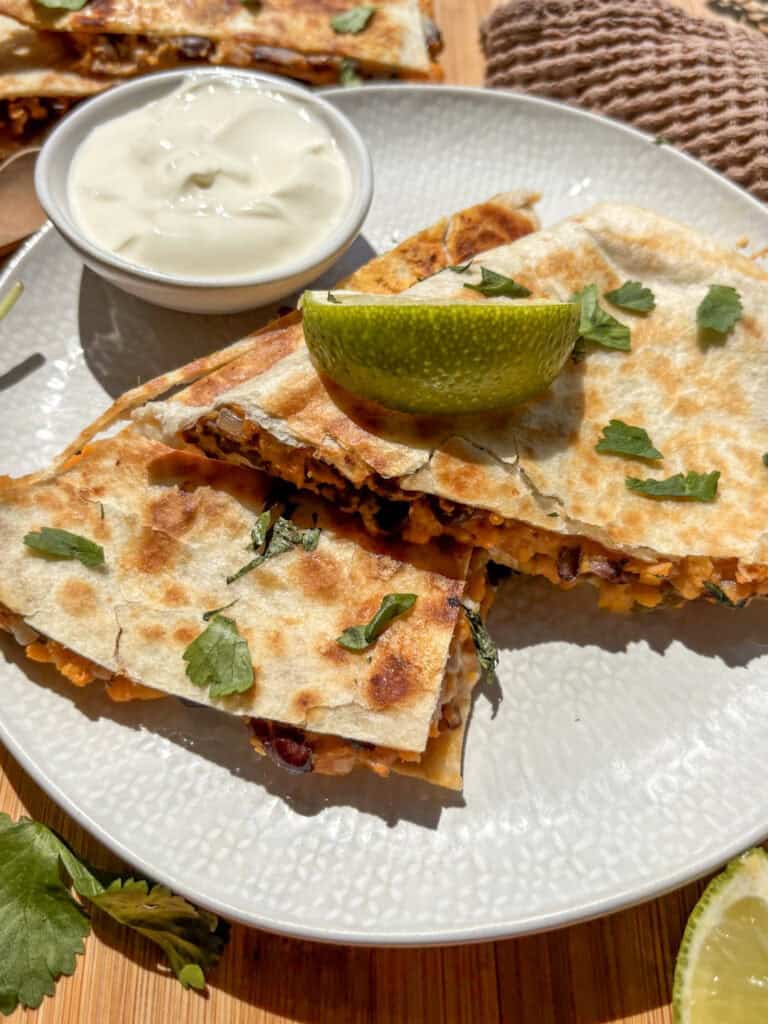 a black bean sweet potato quesadilla with a dip pot of sour cream, topped with a lime wedge
