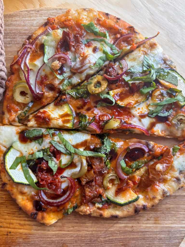 a flatbread pizza topped with Mediterranean veegtables, mozzarella, balsamic glaze, and basil