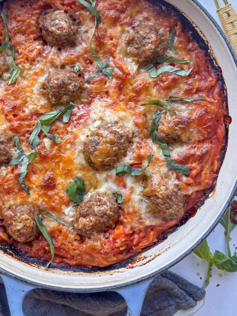 a close up shot of the baked orzo and meatballs with a top layer of melty mozzarella cheese