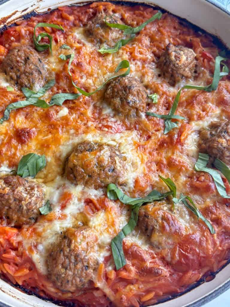 close up shot of cheesy baked orzo and meatballs