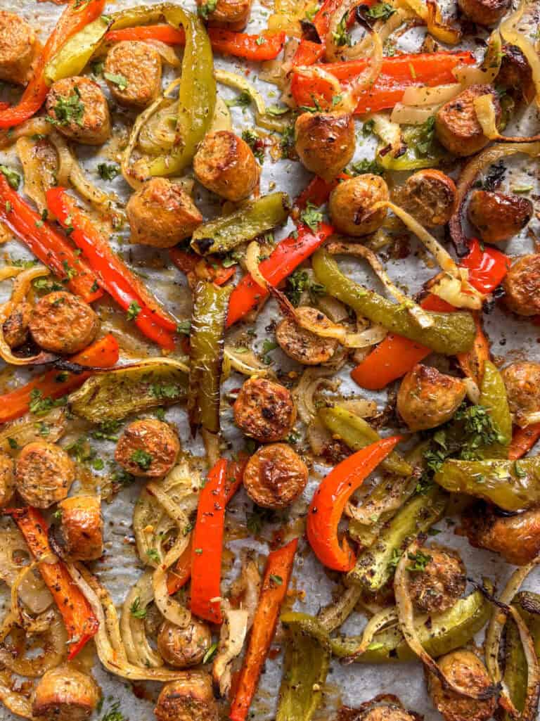 a sheet pan of sausage and peppers roasted in Italian seasonings