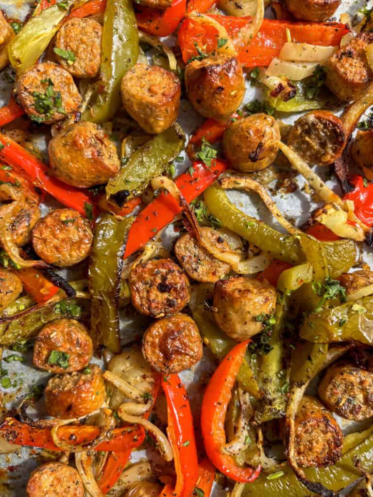 A sheet pan of roasted sausage and peppers seasoned with Italian seasonings
