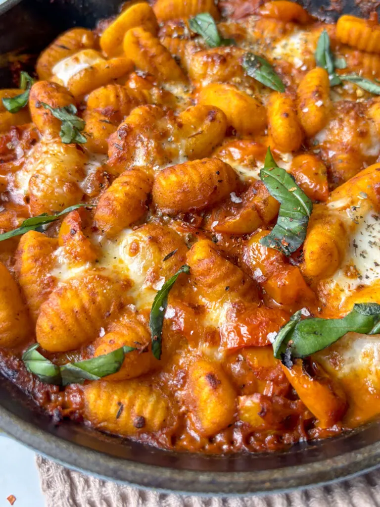 creamy tomato gnocchi topped with melted mozzarella and fresh basil