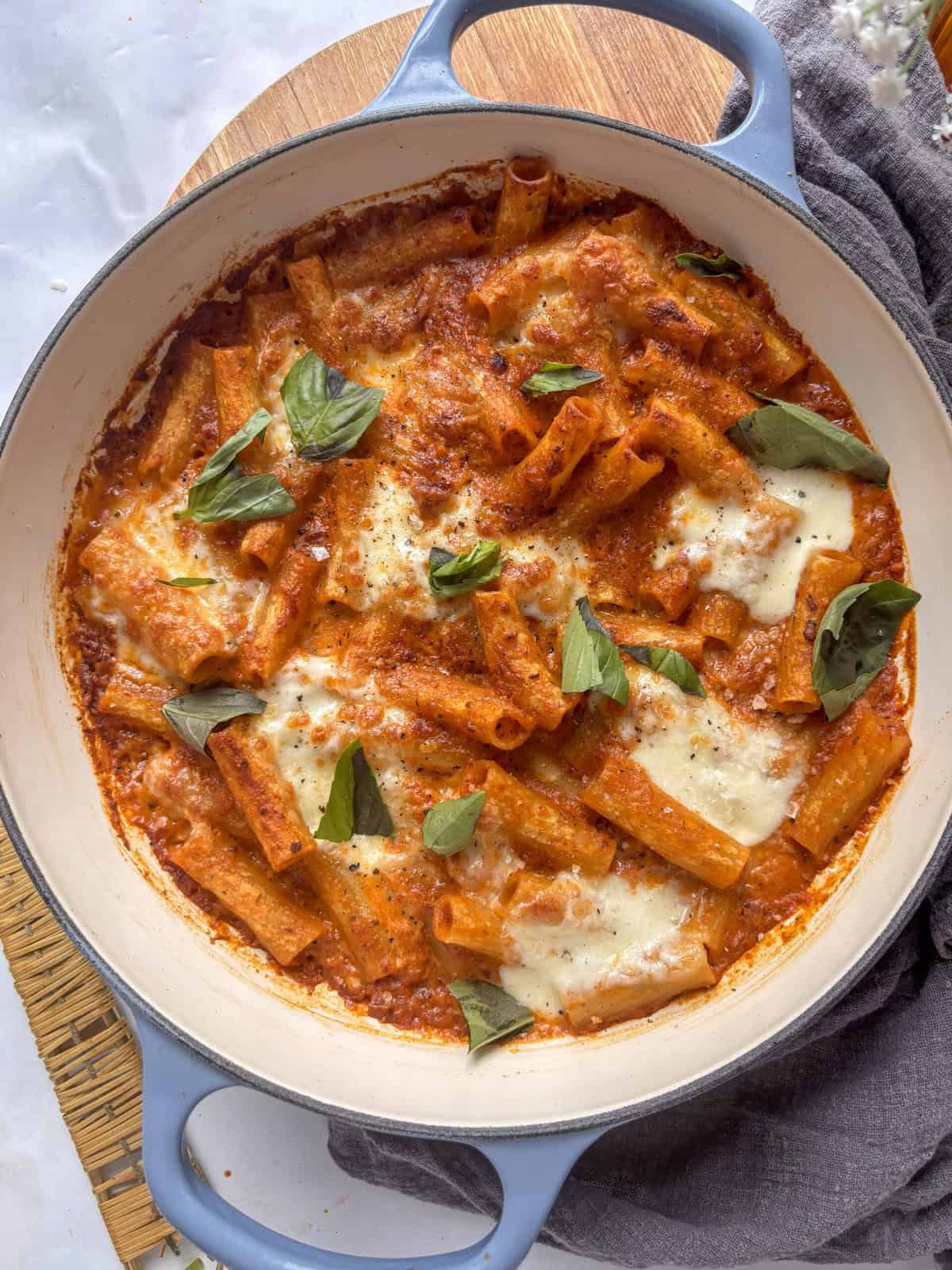 a casserole dish with creamy sun-dried tomato pasta topped with mozzarella and basil